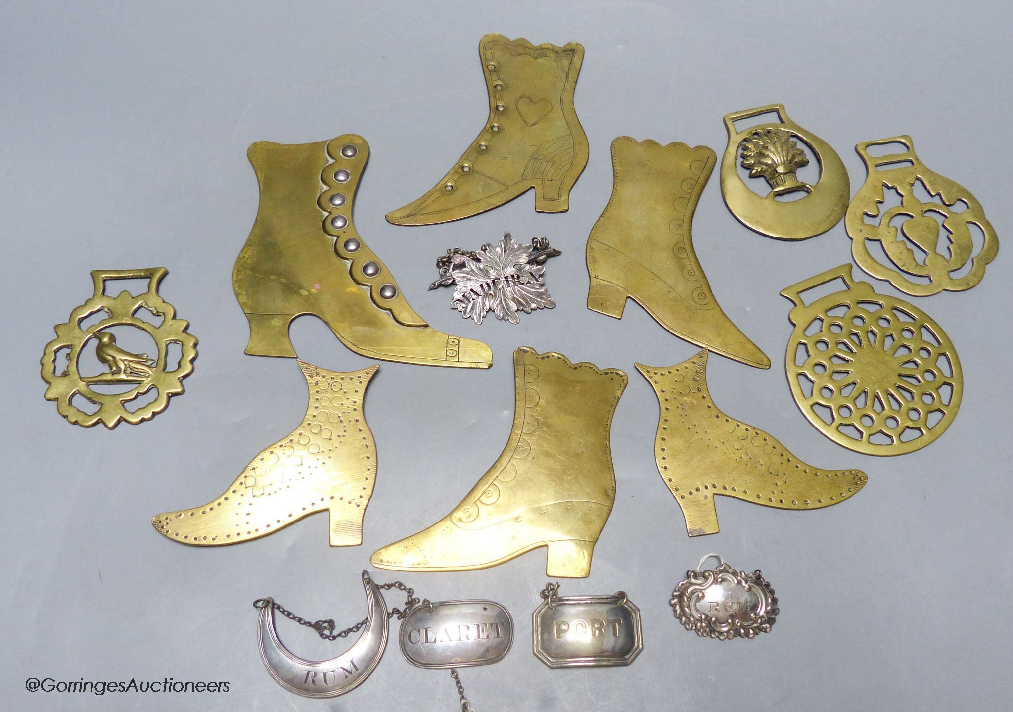 A group of plated wine labels and brass model shoes